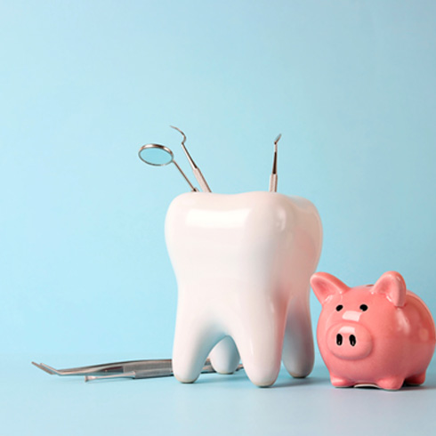 A piggy bank and a model tooth set against a light blue background