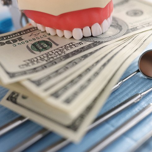 A jaw mockup biting several hundred dollar bills