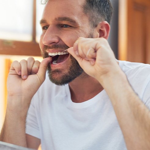 Patient with dental implants in Jersey City flossing