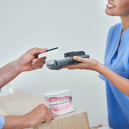 A man using his credit card to pay for dental care