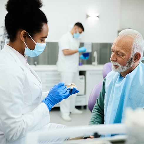 An older man discussing dentures with his dentist