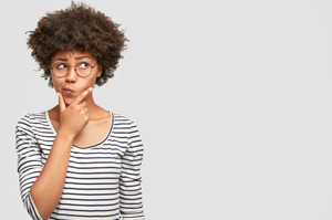 Woman with glasses and striped shirt thinking